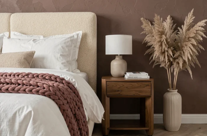 Chambre tendance avec tête de lit en bouclé ivoire, linge de lit blanc et décoration naturelle en tons neutres chauds