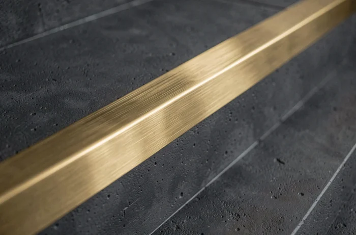 Nez de marche en laiton brossé doré sur des marches en béton anthracite